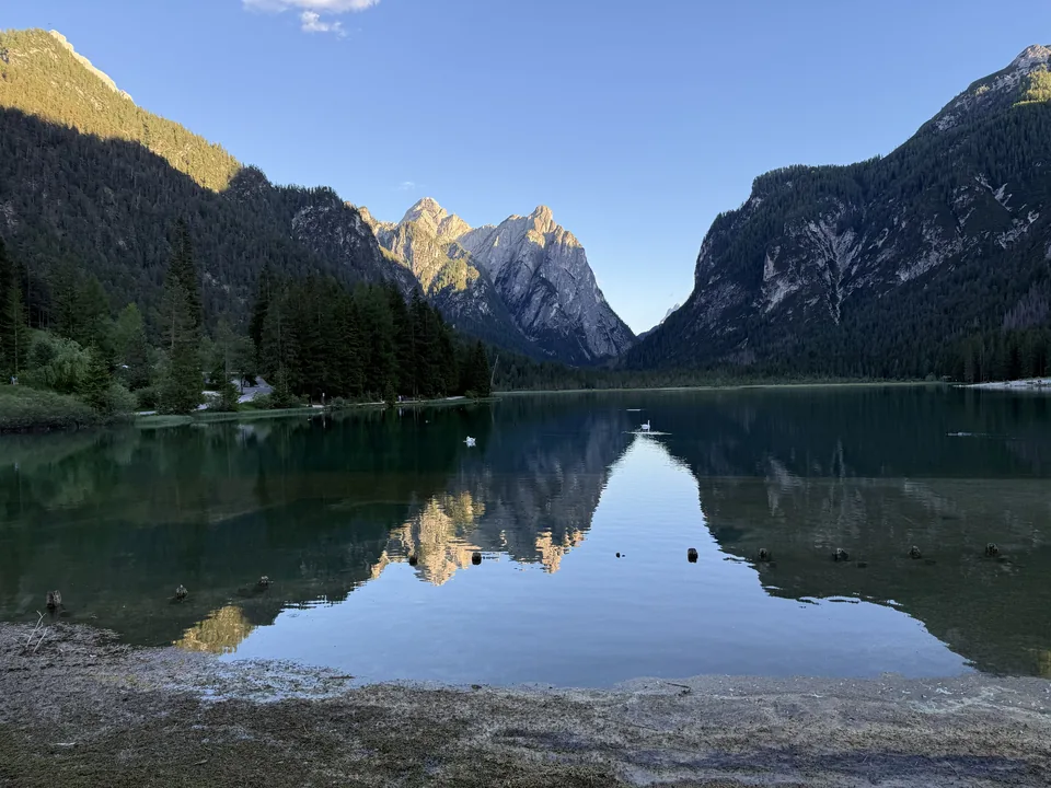 Spiegelung von Bergen und Wald auf einem ruhigen See im Abendlicht